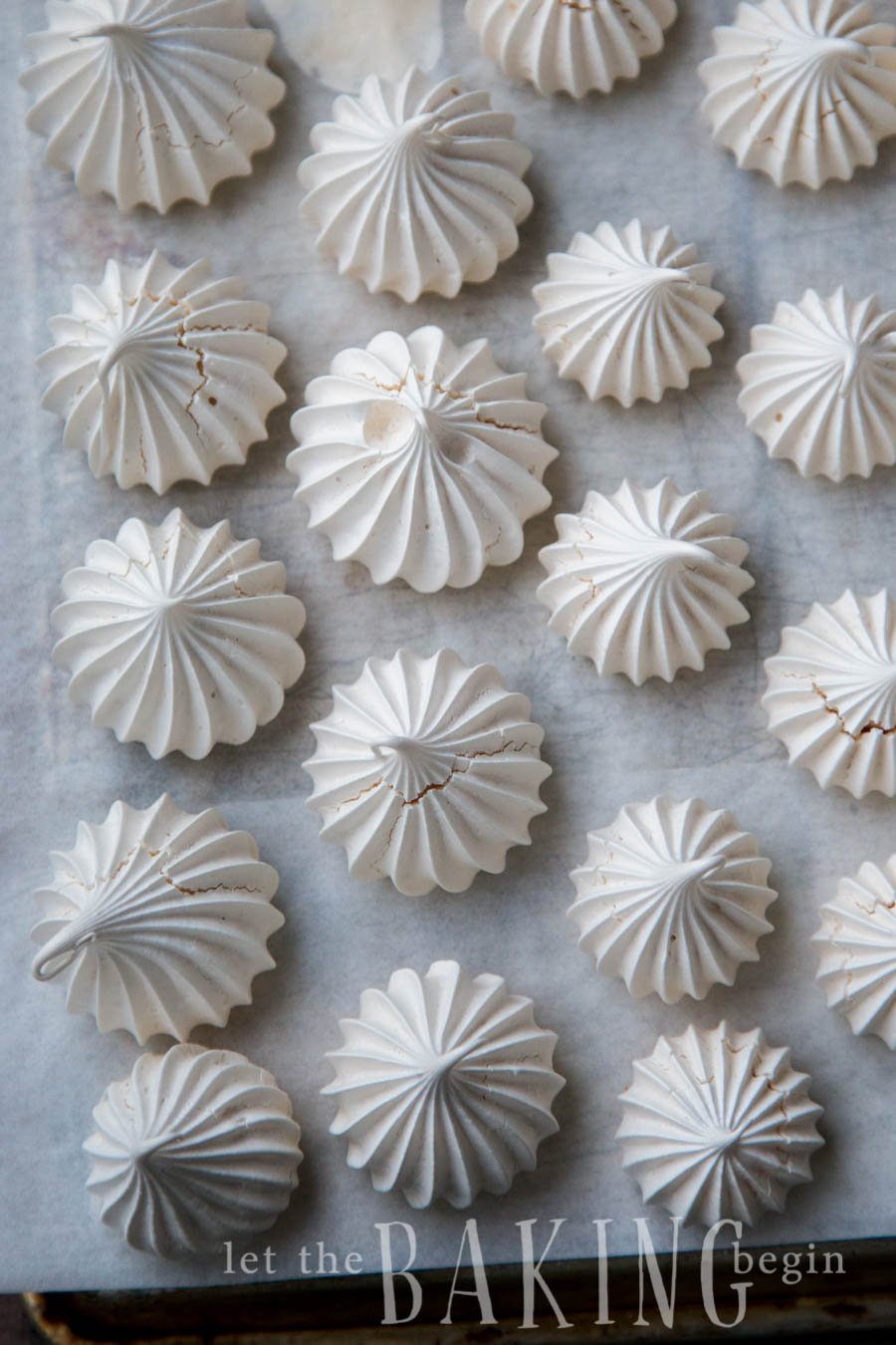 Top view of meringue cookies on a parchment lined baking sheet.