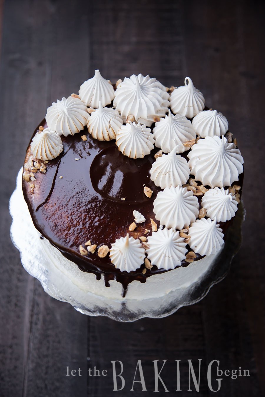 Kiev cake on a platter topped with chocolate, half meringues, and hazelnut.