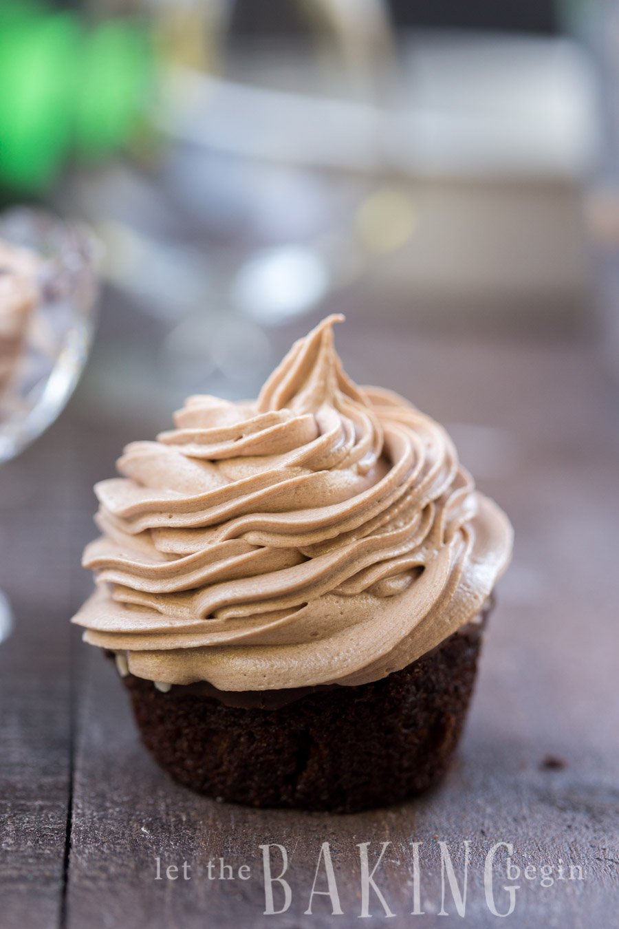 Buttercream frosting on a chocolate cupcake on a wooden table.