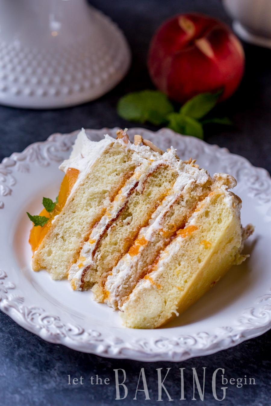 A slice of peaches and cream cake on a plate with peach jam and Chantilly cream. 