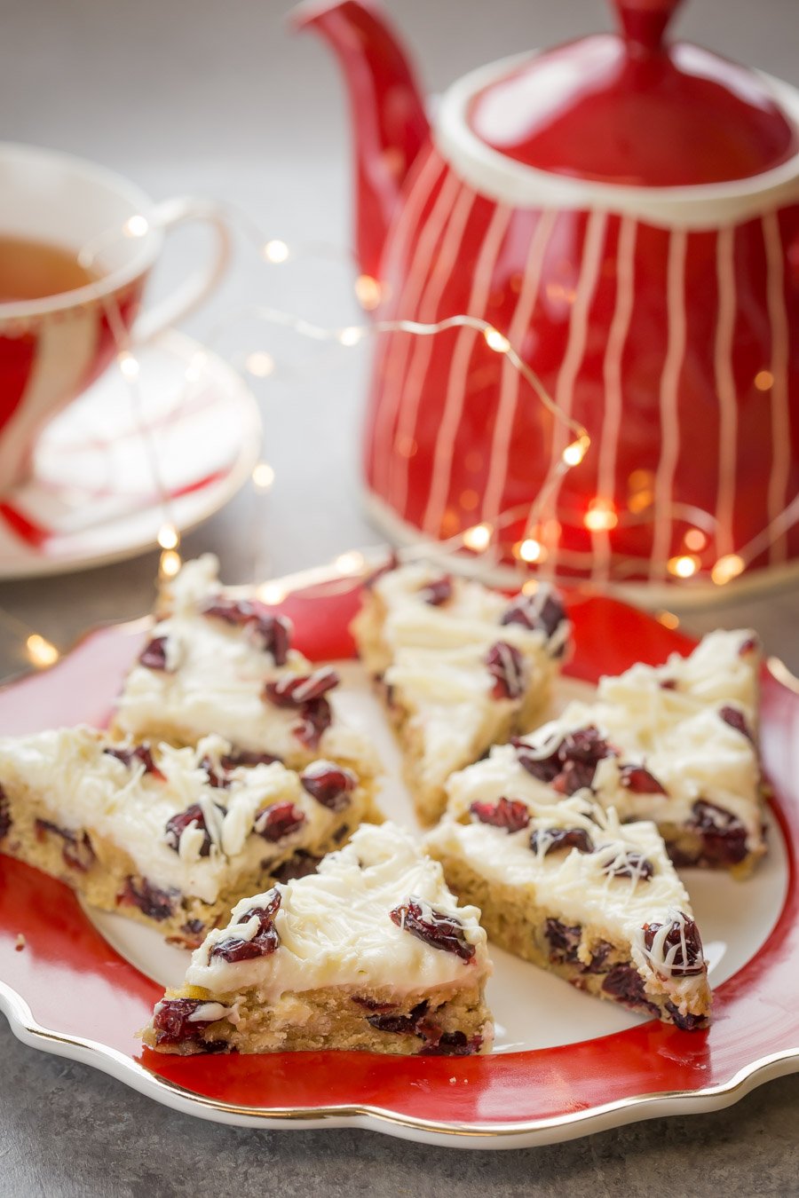 Cranberry bars topped with cranberries and white chocolate on a plate.