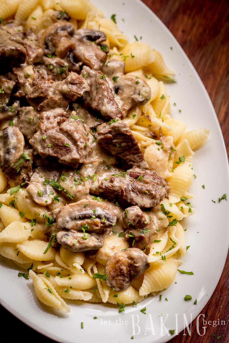 Beef stroganoff topped with fresh greens in a large decorative bowl.