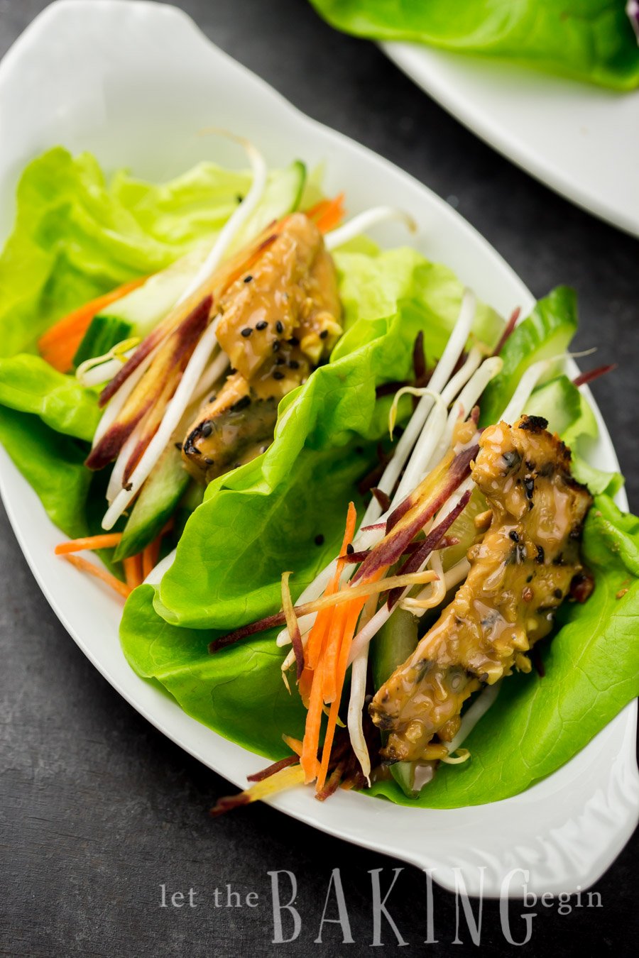 Two lettuce wraps with Thai chicken in peanut sauce on a plate.