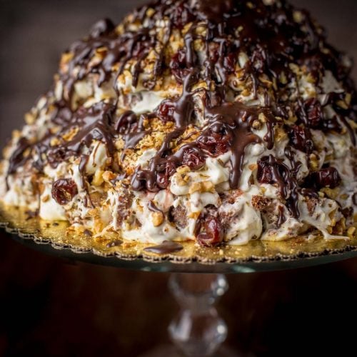 Marble Volcano Cake (Торт "Пинчер") - is made by dipping squares of marbled cake first in spiked cherry juice, then sour cream frosting, and finally stacking it with some cherries and roasted walnut into a stunning mountain of cake. A showstopper, right here, for sure!