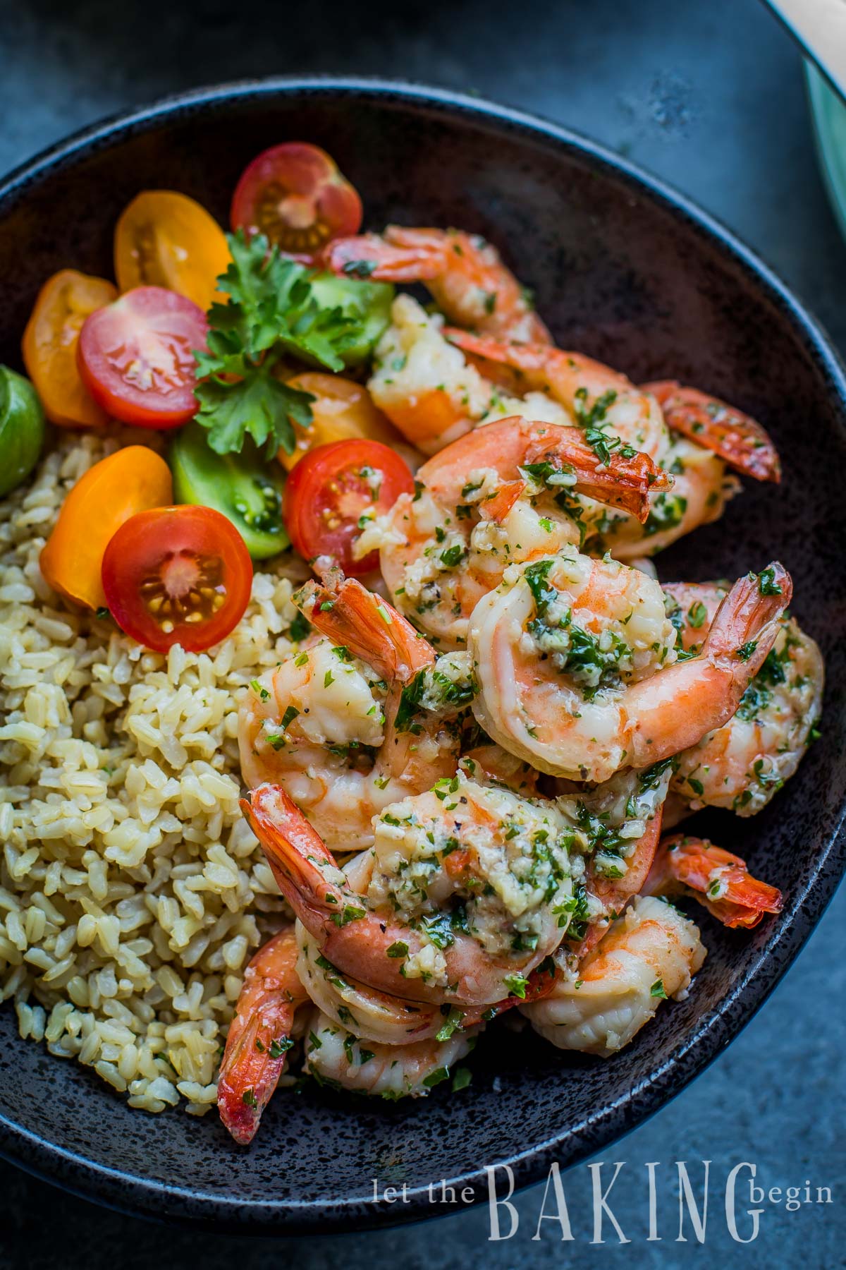 Shrimp with cooked rice and tomatoes with fresh greens in a white bowl.