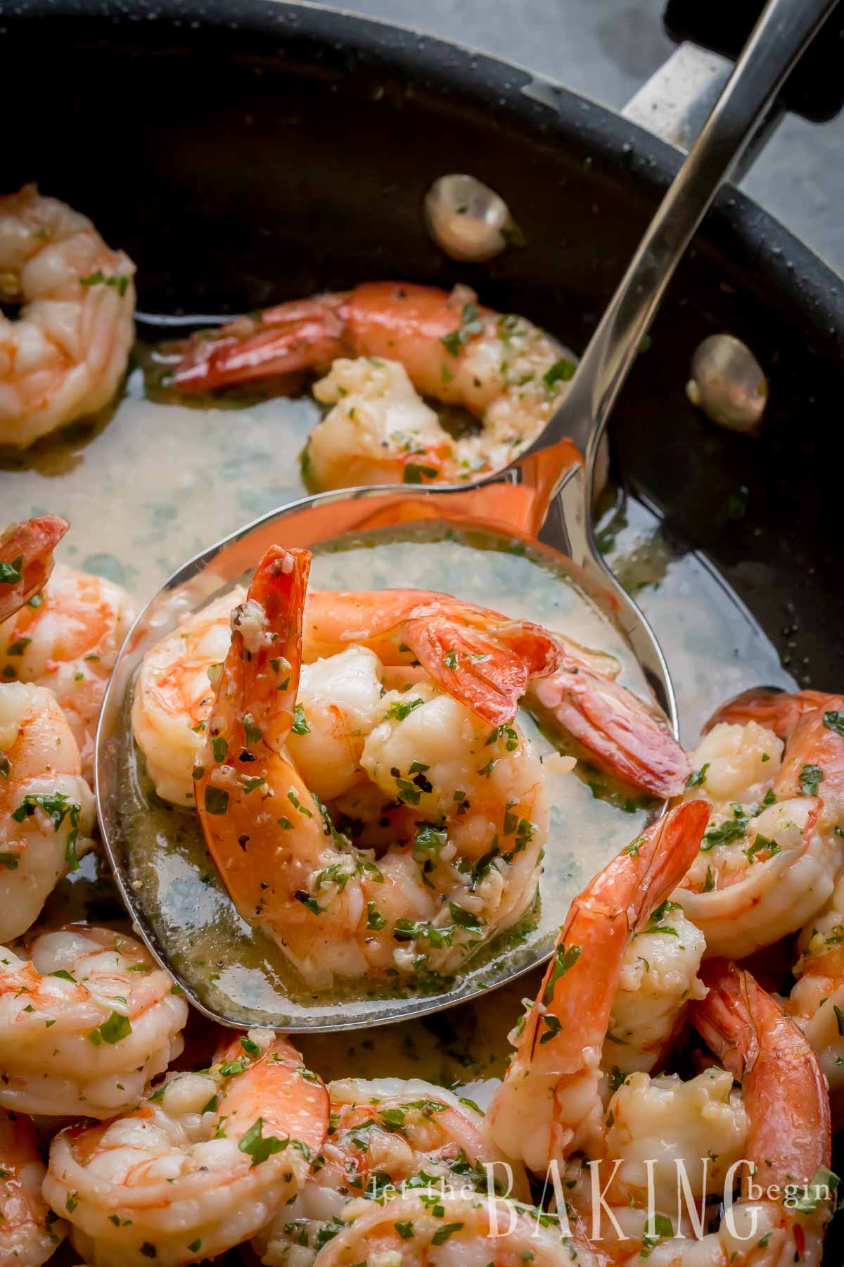Shrimp scampi in a skillet with butter sauce and fresh parsley. 