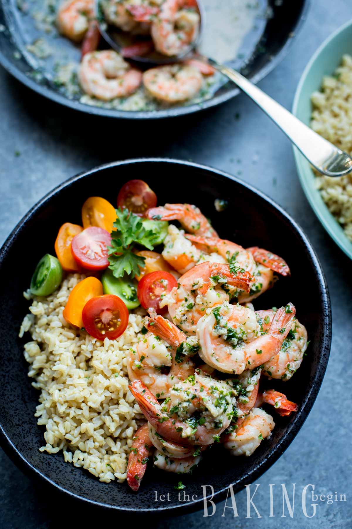 Shrimp scampi in a bowl with quinoa and tomatoes next to a bowl of shrimp.