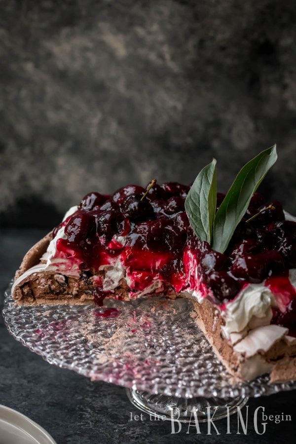 Chocolate Pavlova Cake topped with Whipped Cream and Cherry Sauce