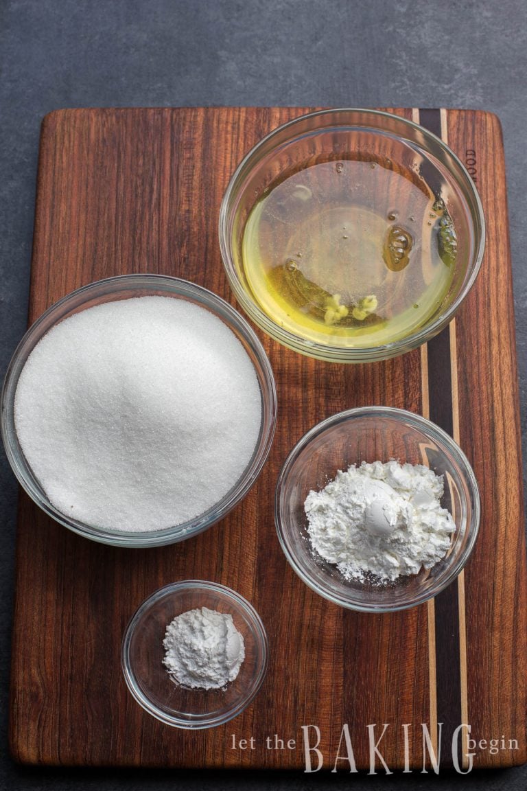 Pavlova meringue ingredients on a wood board: egg whites, granulated sugar, cornstarch and cream of tartar