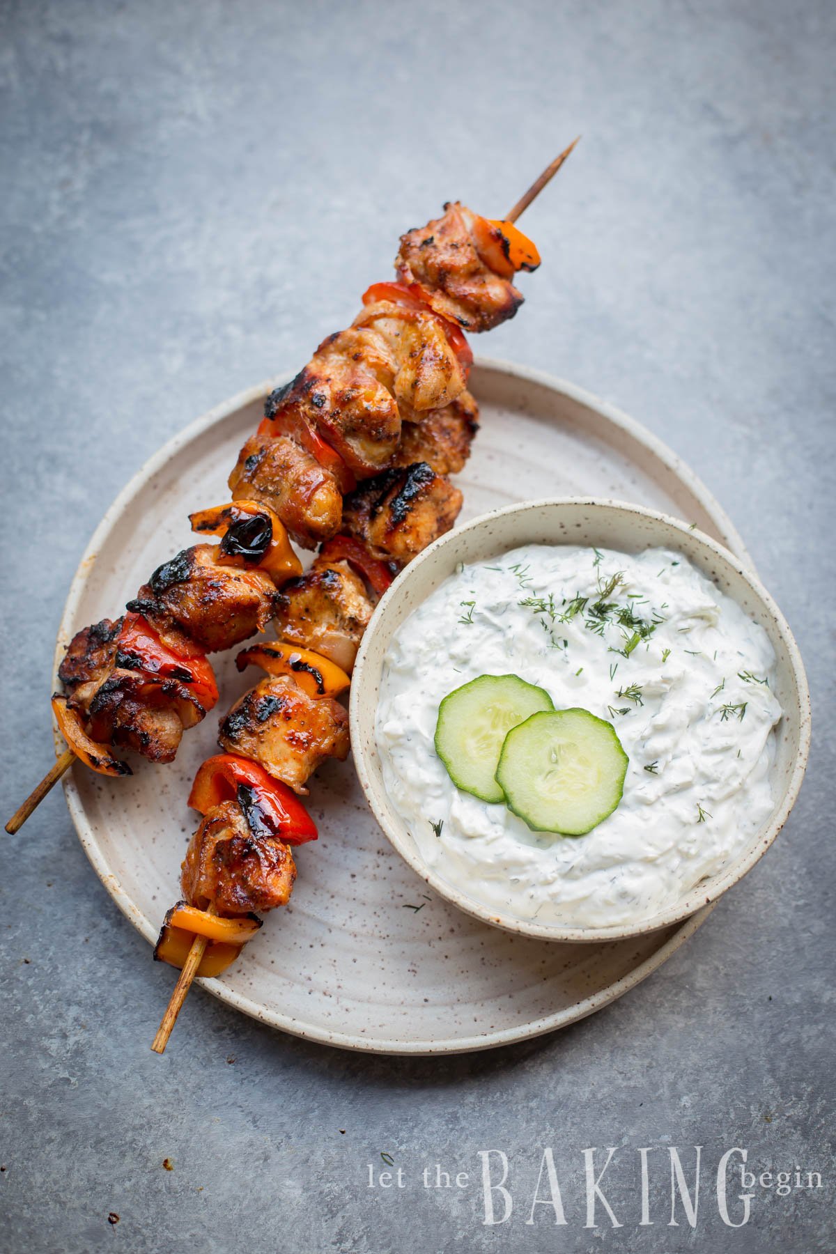 Homemade tzatziki sauce with fresh dill and cucumber with skewered chicken kabobs.