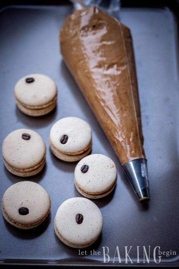 Coffee Macaron Recipe is a combination of a creamy coffee flavored white chocolate ganache and a basic macaron shell. They make amazing treats to go with coffee or tea, or as part of a potluck dessert tables at baby showers, birthdays or any other parties.
