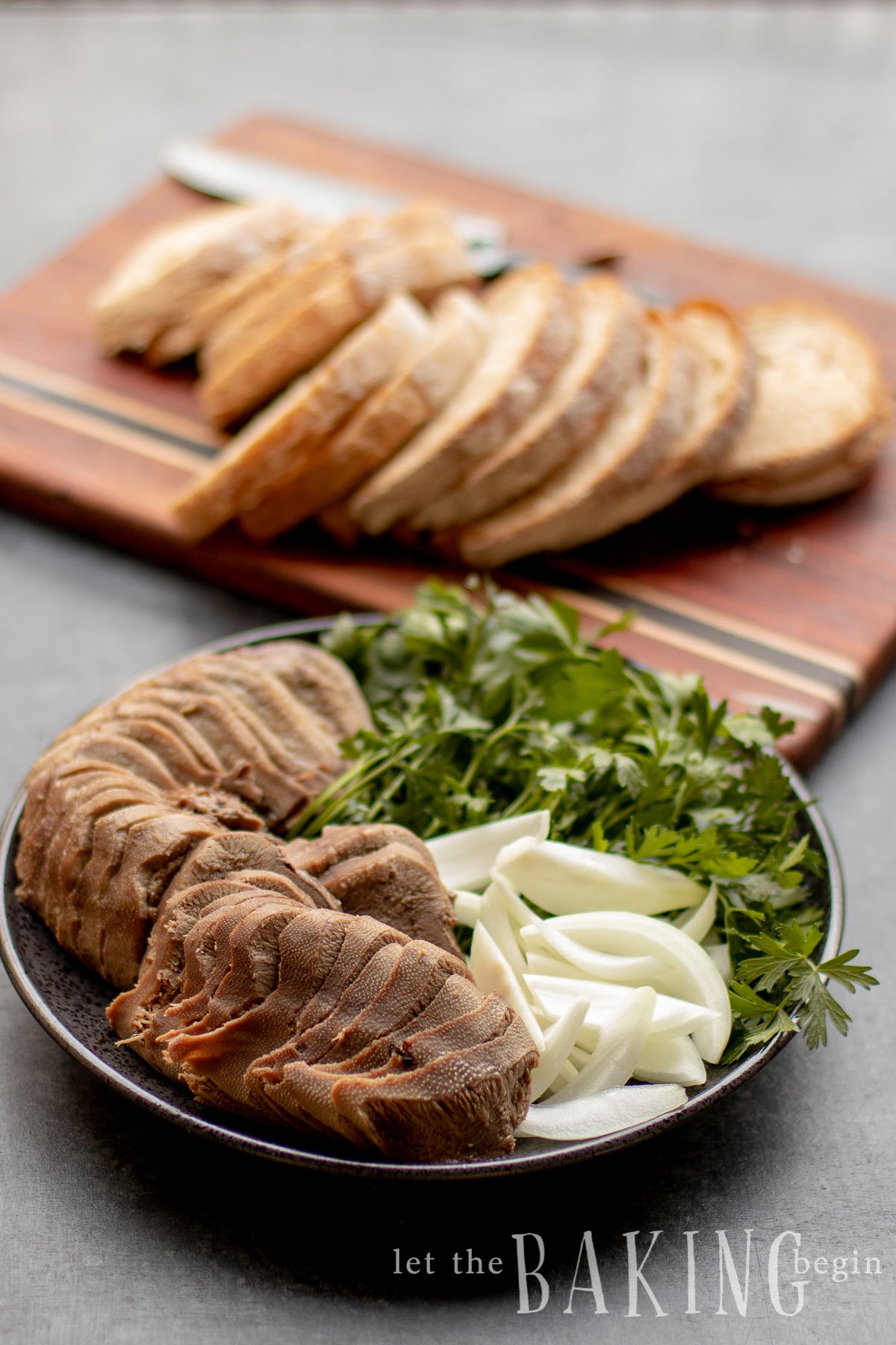 How to cook beef tongue. Sliced tongue on a platter with herbs, sliced onions and toast