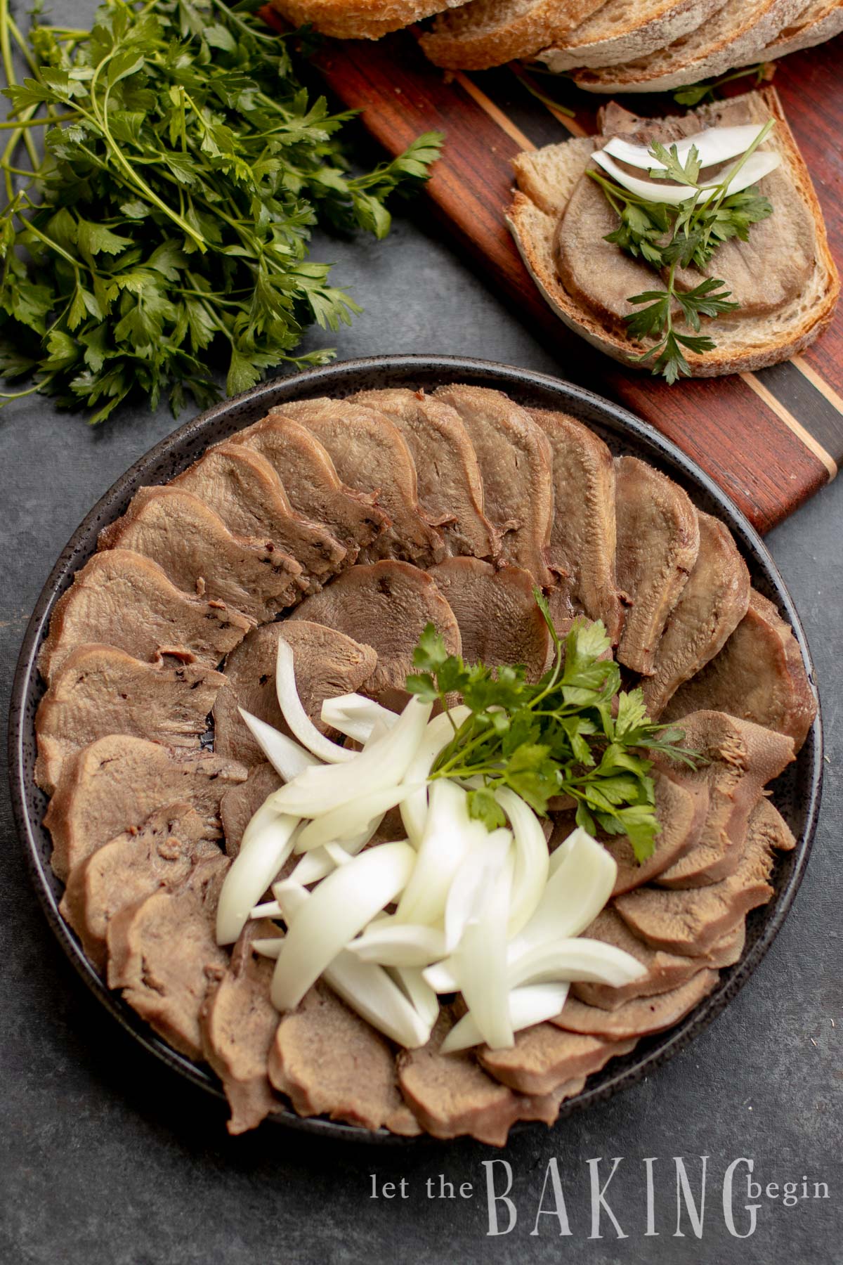 Beef tongue sliced and styled on a platter, topped with onions and herbs.