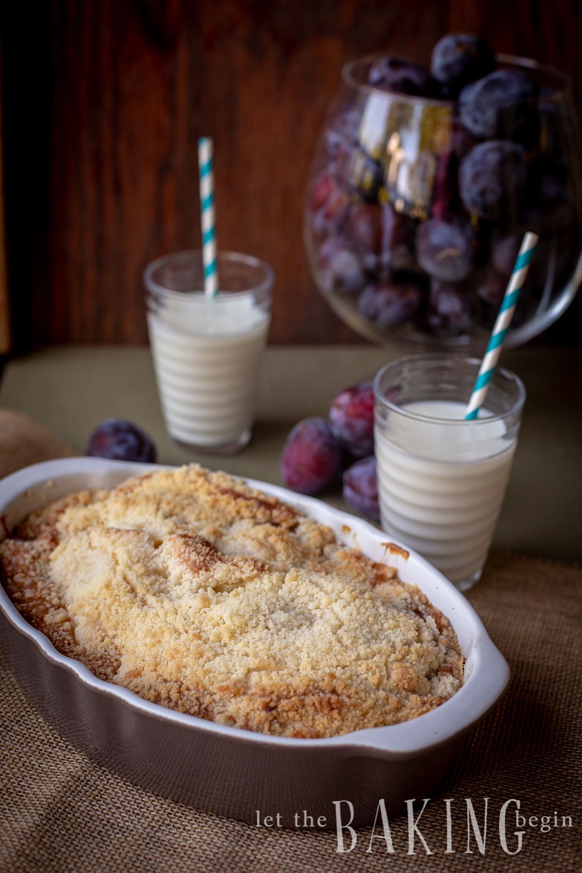 Coffee cake in a casserole dish with two glasses of milk with straws.