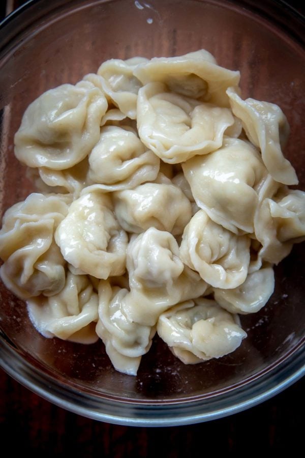 Chicken Pelmeni tossed with melted butter - tiny homemade dumplings made with soft and easy to make dough, then filled with juicy ground chicken filling. 