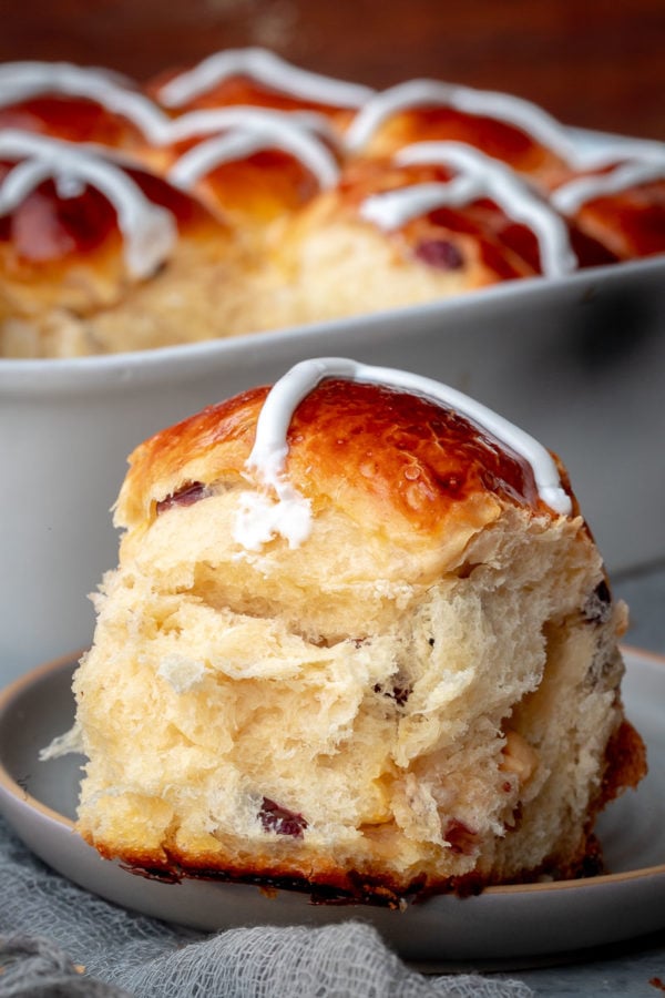 Hot Cross Bun on a plate, showcasing the fluffiness of the bun.