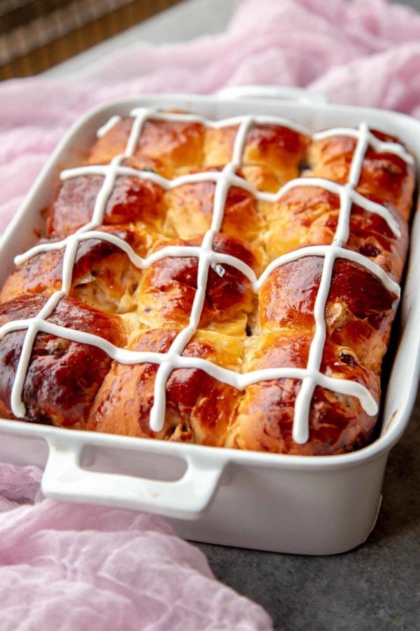 Hot Cross Buns with Powdered Sugar Glaze in a baking dish.