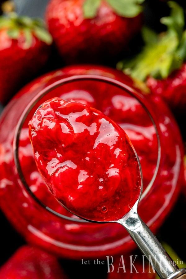 Strawberry Topping in a spoon over a glass with the strawberry sauce. Shot from the top.
