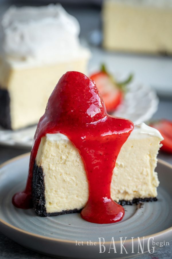 Slice of cheesecake with a whole strawberry and strawberry sauce on top.