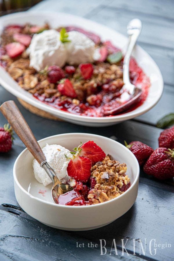 Strawberry rhubarb crisp recipe with serving dish in background and individual portion of strawberry rhubarb crisp in bowl served with vanilla ice cream. 