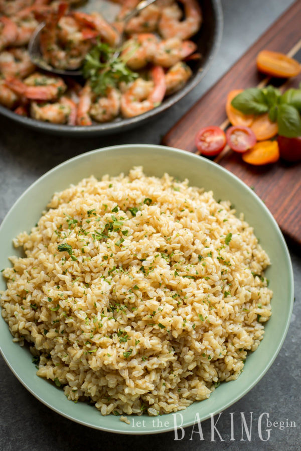 Pressure cooker brown rice in a bowl with a skillet of shrimp in the background.