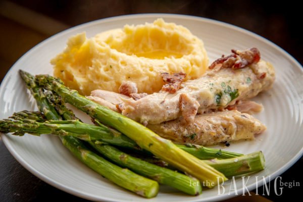 Plate with servings of a chicken bacon recipe, asparagu, and fluffy mashed potatoes. 