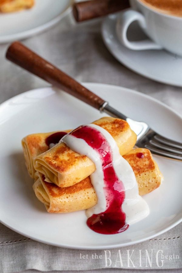 Stack of cheese blintz on a white plate with a fork