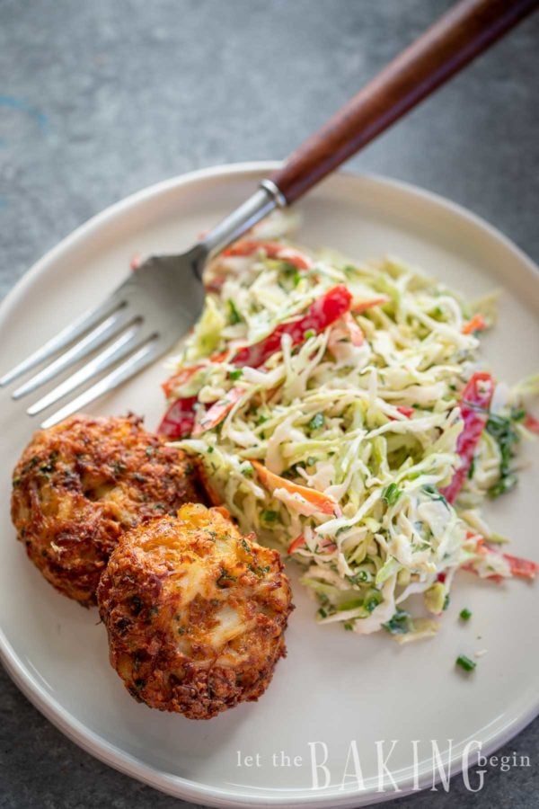 Crab cake recipe made on a plate with coleslaw on the side.