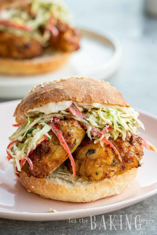 Two crab cakes in a bun with coleslaw