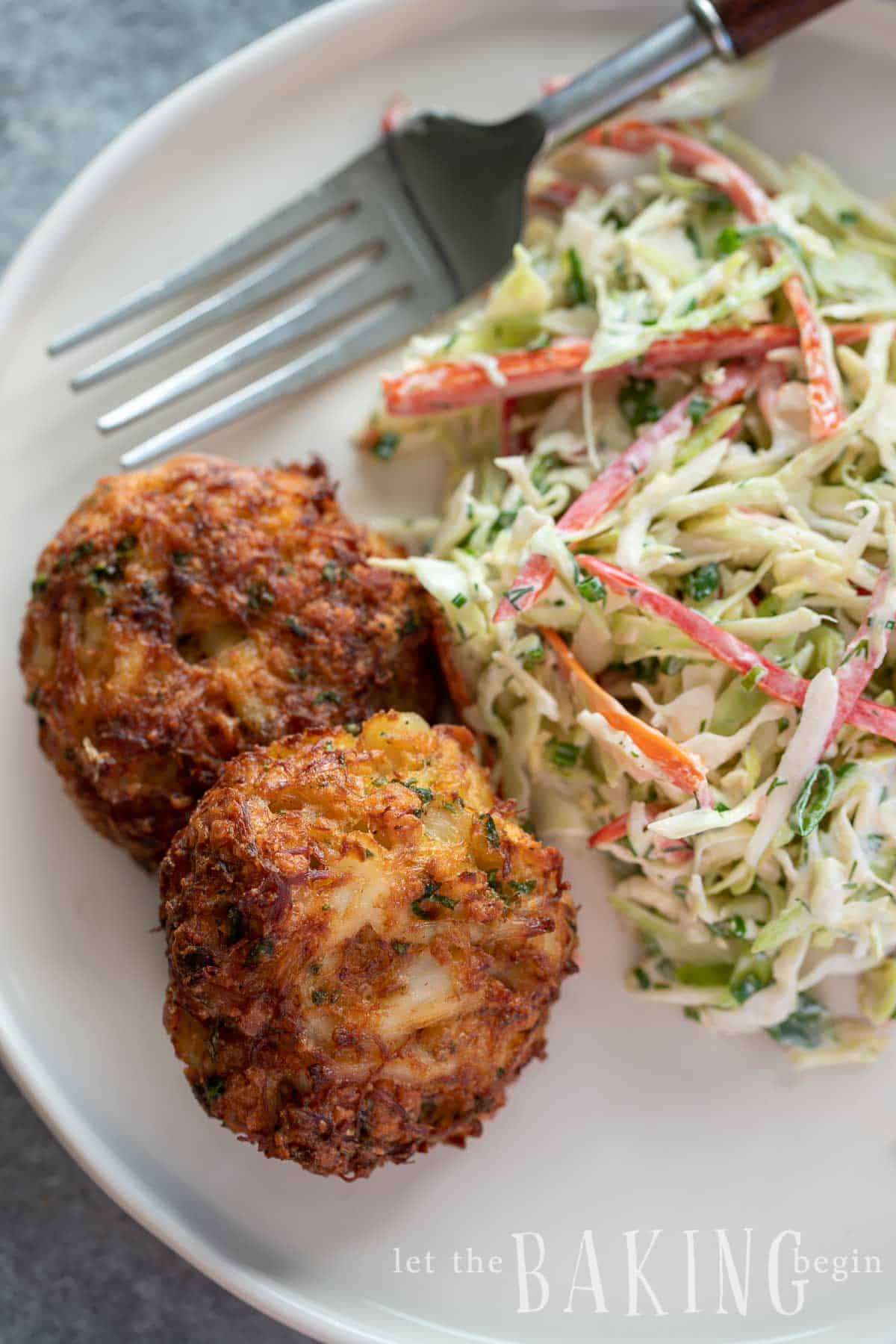 Crab cake recipe made on a plate with coleslaw on the side.