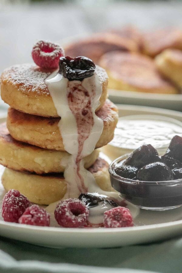 Syrniki pancakes stacked and topped with berries