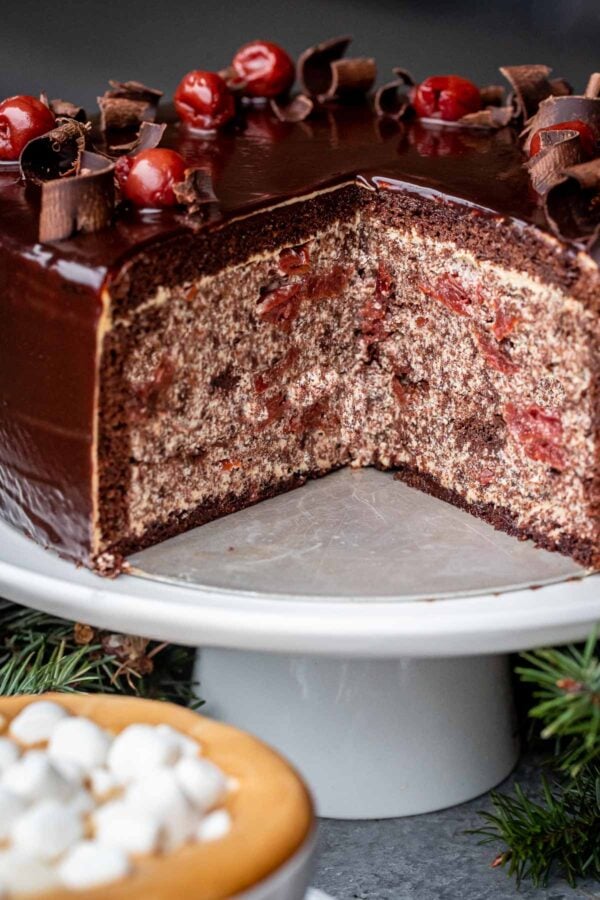 The Chocolate Cherry cake on a cake stand with a piece removed, showing off the inside of the cake. 
