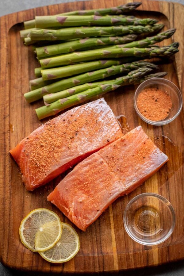 Ingredients for Air Fried Salmon and Asparagus laid out on a wooden cutting board.
