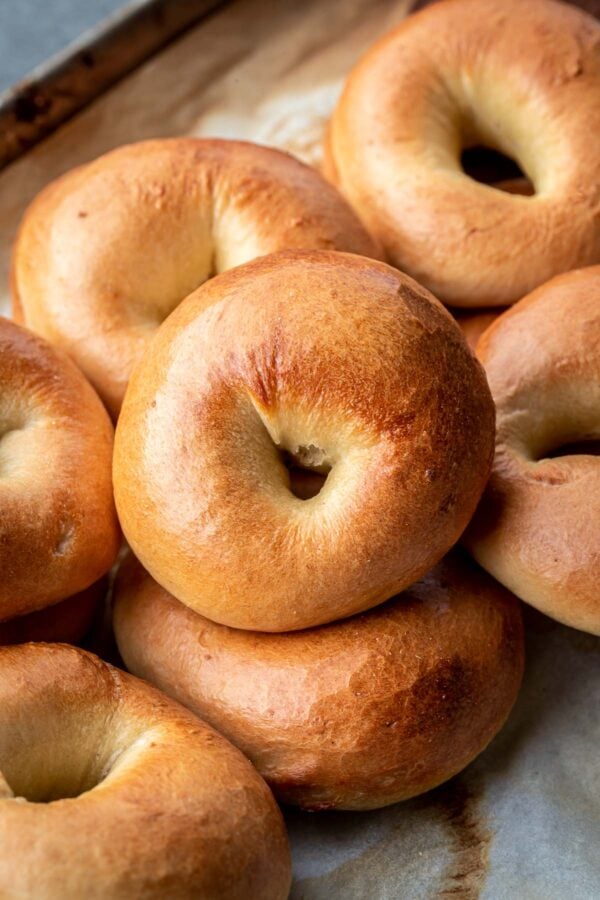 Bagels stacked in a baking sheet.