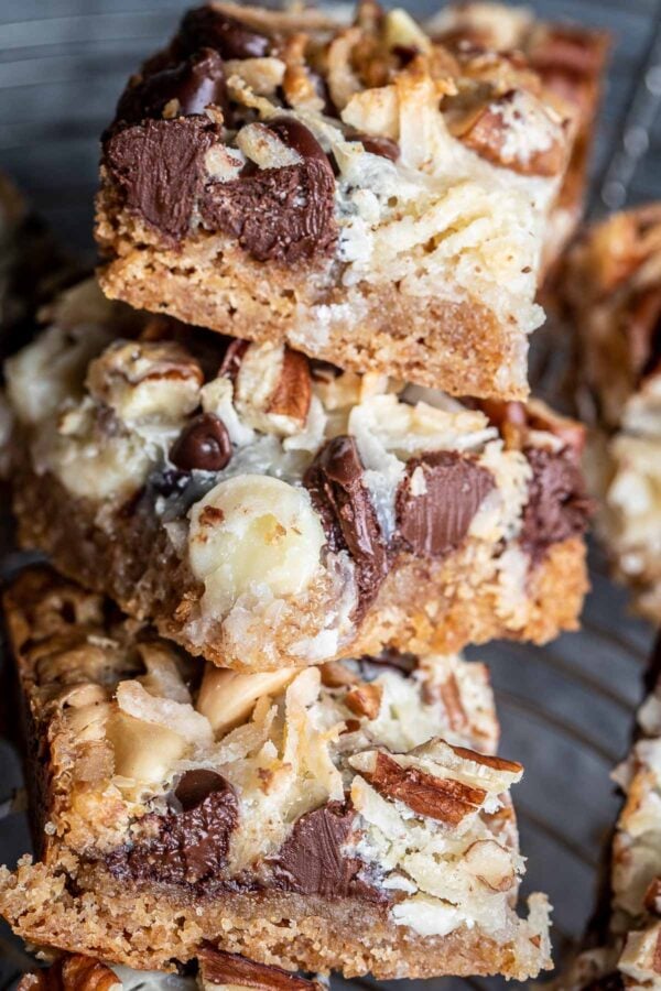 Stack of 7 layer bars (also called magic cookie bars) showing the layers of graham crackers, coconut, chocolate, and nuts.