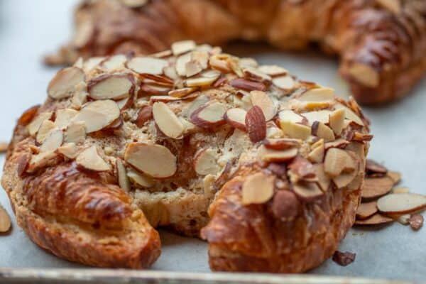 Close up shot of almond croissant, displaying crispy almond exterior and toasted almonds on top.
