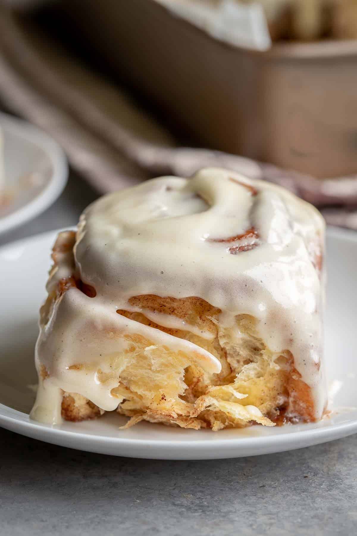 Cinnamon Roll on a plate with warm cream cheese icing on top. 