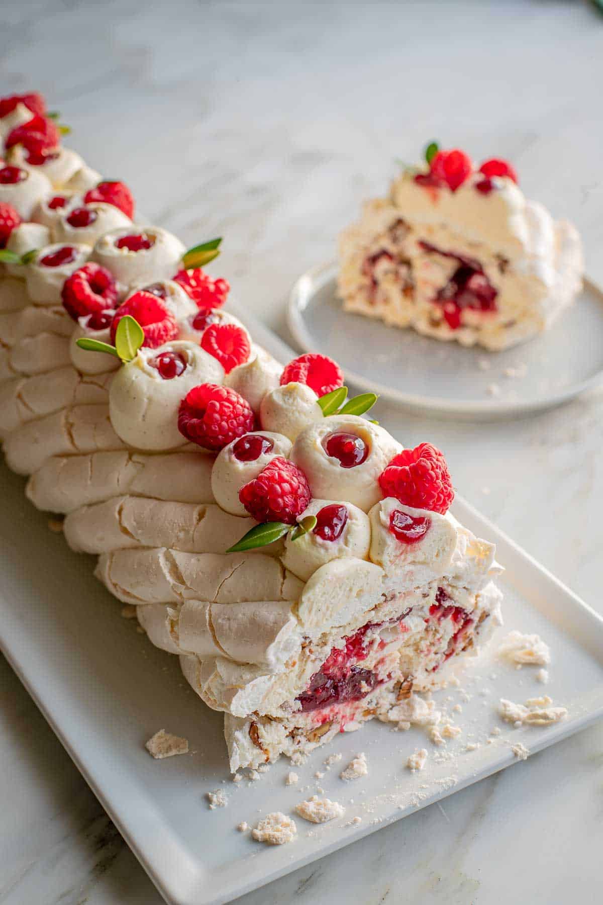 Top view of the meringue roulade with a slice of the meringue roulade in the background.