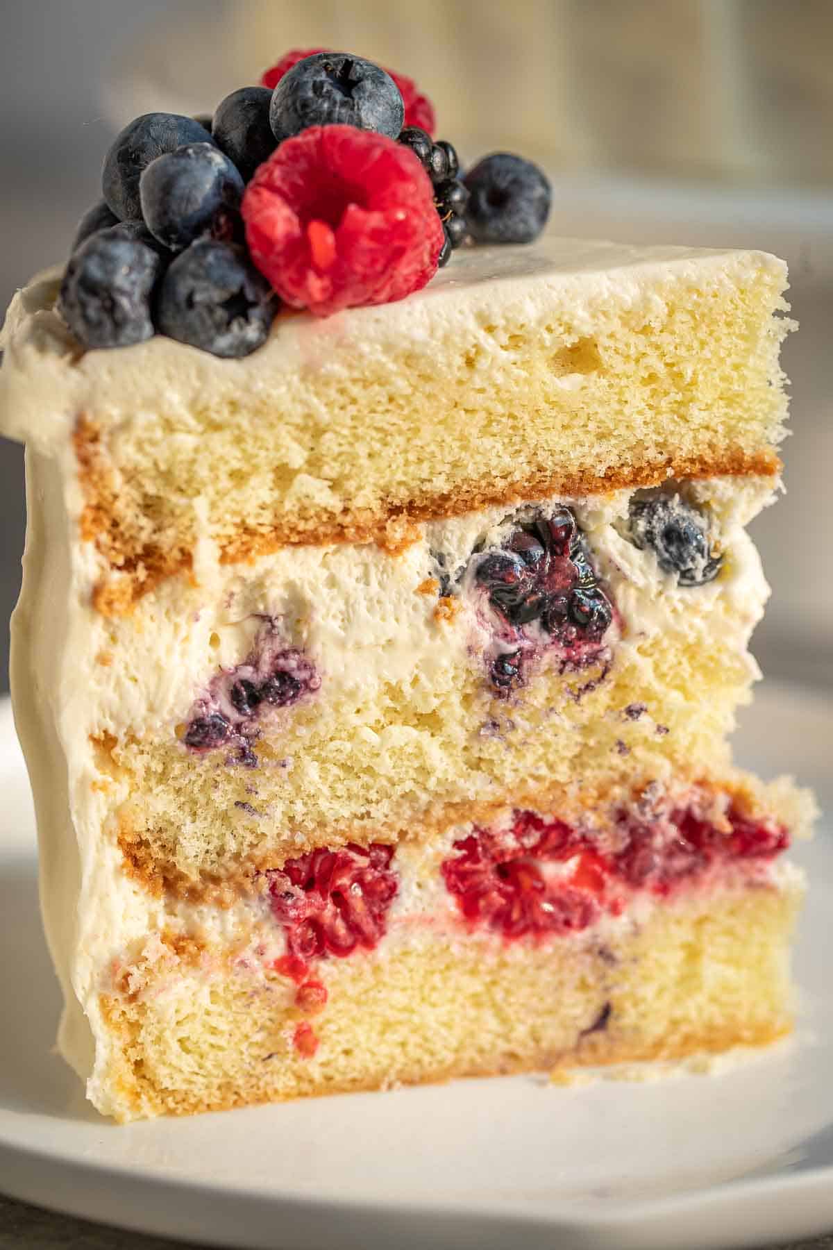 A view of the side of the cake slice with sponge cake, chantilly cream and the berries exposed.