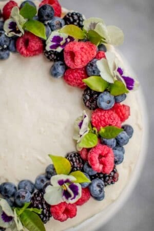 Top view of Chantilly Cake with berries and flowers as a wreath.