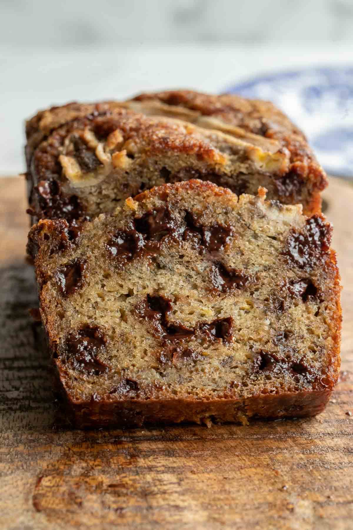 Chocolate chip banana bread with a slice leaning against the loaf on a cutting board