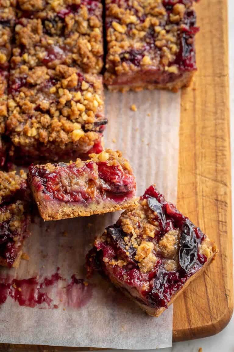 Plum crumble bars cut into squares and stacked on parchment paper