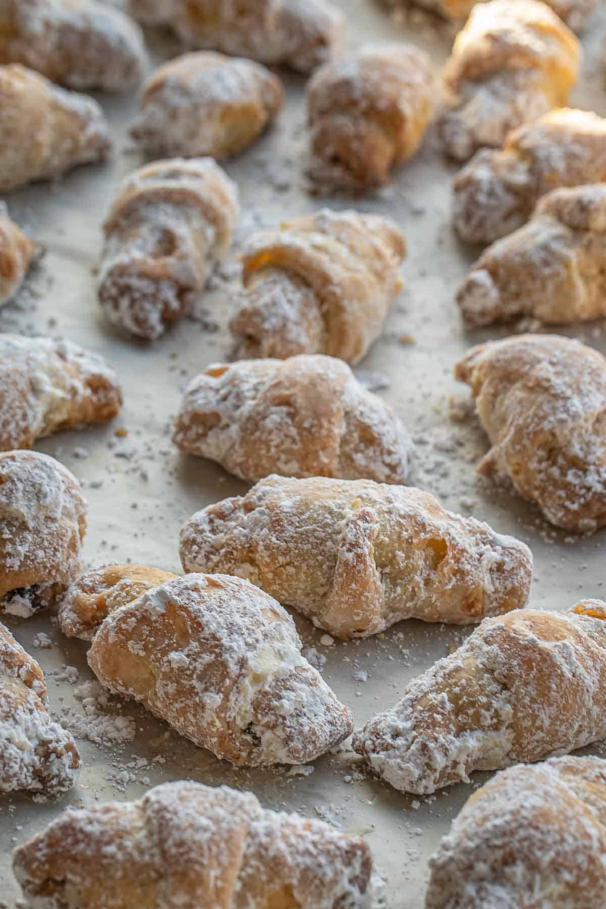 Rogaliki recipe - Ukrainian cream cheese pastries dusted with powdered sugar on a baking sheet