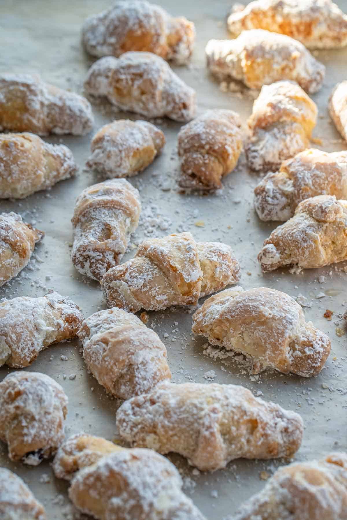 A tray of rogaliki dusted in powdered sugar ready to store or serve
