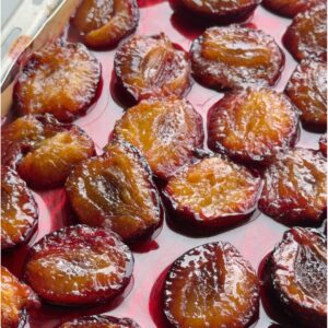 Candied plums roasted in sugar, glossy and caramelized in their own ruby syrup on a parchment-lined sheet pan