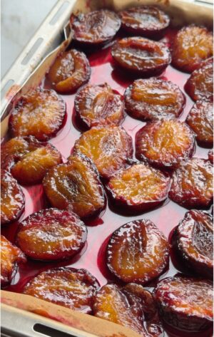 Candied plums roasted in sugar, glossy and caramelized in their own ruby syrup on a parchment-lined sheet pan