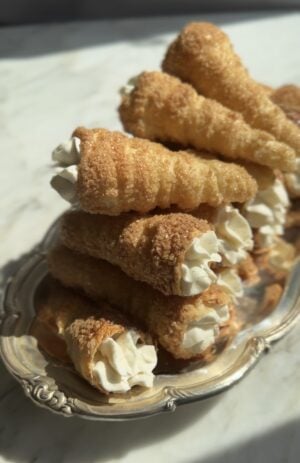 Puff pastry cream horns filled with cream on a silver platter