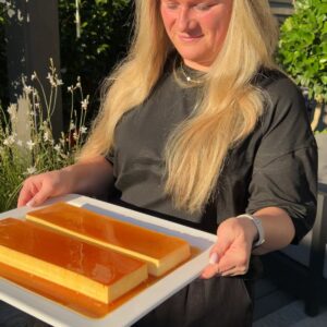 Two loaf-pan flans on a white platter with caramel sauce, a double batch of this flan recipe