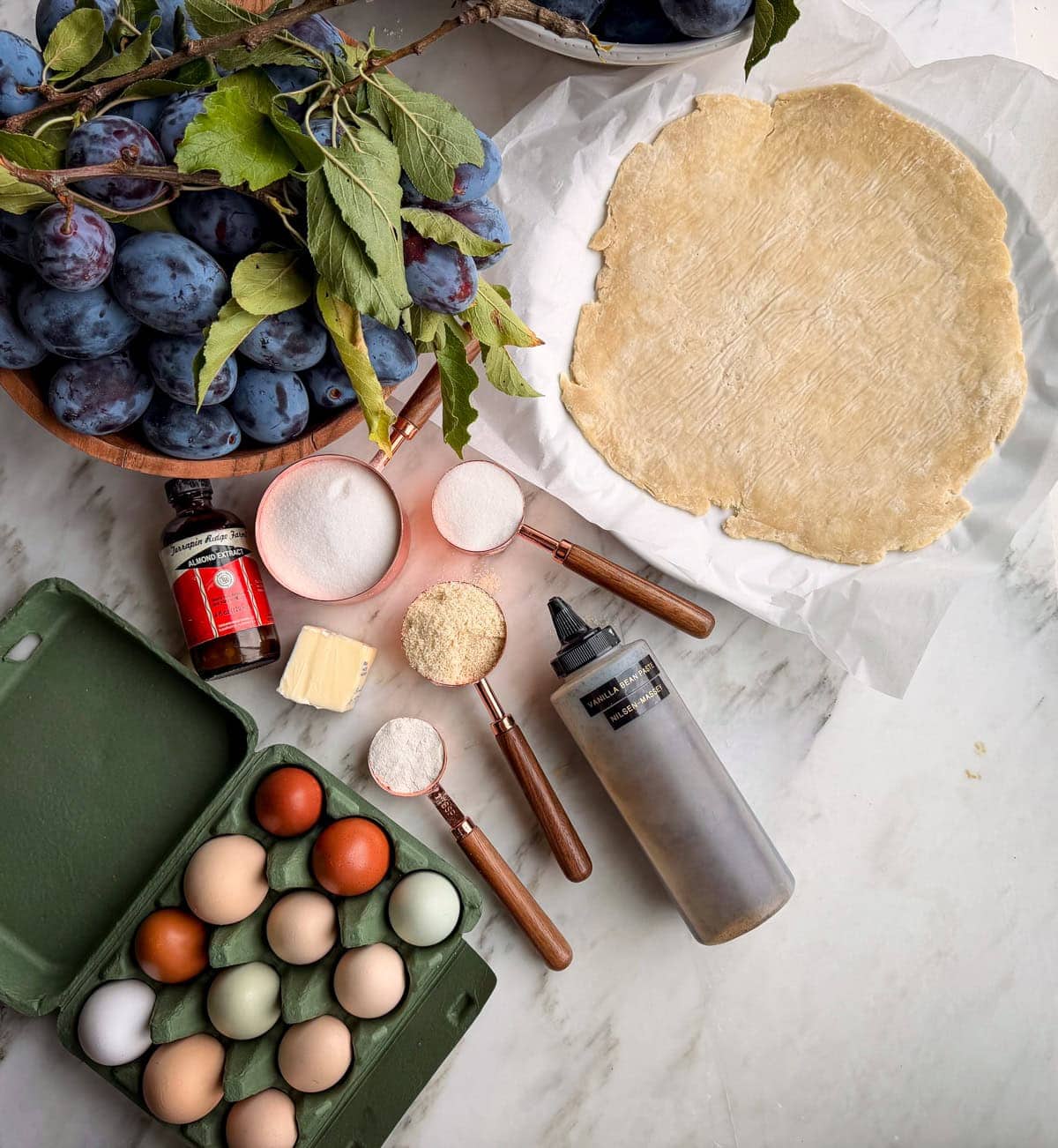 Ingredients for an Italian plum galette with almond cream laid out on marble