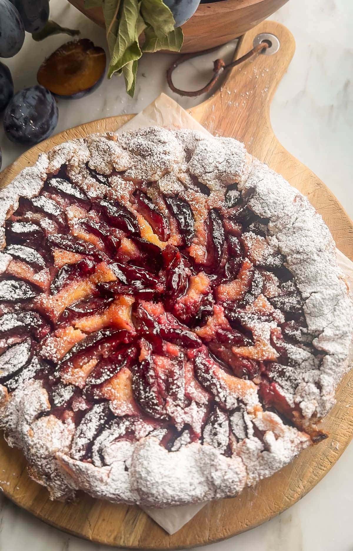 Overhead view of a plum galette with almond cream, dusted with powdered sugar